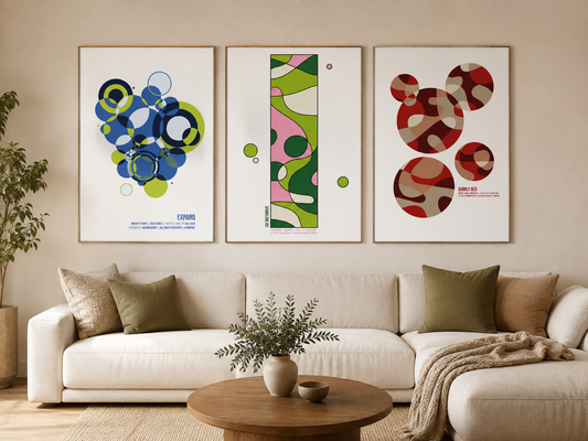 Three colorful abstract Indy Art Studio posters displayed above a cream sofa in a warm, neutral living room.